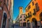 Street with old colorful buildings with italian flag on wall and tower in medieval historical city centre of Padua