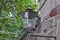 Street old lantern, made of metal, suspended on a stone wall, in the territory of a medieval fortress, one summer day