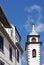 Street of old white painted houses and the bell tower of the historic parish church of saint peters in funchal madeira