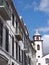 Street of old white painted houses and the tower of the historic parish church of saint peters in funchal madeira famous for being