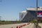 A street with orange cones and cars driving surrounded by Mercedes-Benz Stadium, lush green trees with a gorgeous clear blue sky