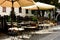 Street patio or terrace with tables, chairs and beige canvas parasols