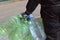 Street photo. Rear view of a man carrying several empty plastic bottles for drinking water.