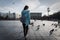 Street Photography: A girl tourist walks around the town square among pigeons. A backpack at the back.