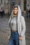 Street portrait of a beautiful young and cheerful woman 25-30 years old with blonde hair and a gray hoodie against the background