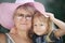 Street portrait of the grandmother with the granddaughter in a pink summer hat