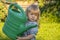 Street portrait of a little girl 2 years old with a garden watering can in her hands. Concept: a fair-Haired child helps