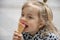 Street portrait of a little girl eating red ice cream in a cone waffle cone. Concept: sweetness for children, summer heat, satisfy