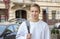 Street portrait of a smiling young guy 20-25 years old with a backpack on his shoulder against the background of old urban archite