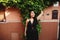 Street portrait of a woman in black dress, on the background of a terracotta wall and green leaves