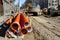 Street reconstruction site, stacked plastic sewage pipes, vertical well, excavator, dewatering pump