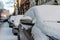 In the street side parked cars covered with snow