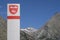 Street sign with the name Saas-Fee on it, a wintersports city in Switzerland with mountains and a blue sky on the