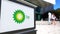 Street signage board with BP logo. Blurred office center and walking people background. Editorial 3D rendering