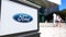 Street signage board with Ford Motor Company logo. Blurred office center and walking people background. Editorial 3D