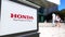 Street signage board with Honda logo. Blurred office center and walking people background. Editorial 3D rendering