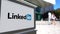 Street signage board with LinkedIn logo. Blurred office center and walking people background. Editorial 3D rendering 4K