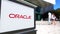 Street signage board with Oracle Corporation logo. Blurred office center and walking people background. Editorial 3D