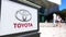 Street signage board with Toyota logo. Blurred office center and walking people background. Editorial 3D rendering