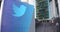 Street signage board with Twitter, Inc. logo. Modern office center skyscraper and stairs background. Editorial 3D