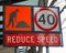 Street signage warning to reduce speed for workmen in the street
