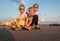 Street sports: A boy and two girls in sunglasses sit together on a large longboard. The summer solchechny frame.