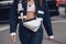 Street style, woman wearing Prada outfit: pale pink cropped top from Prada, white leather cross body bag, navy blue denim jacket