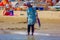 Street vendor who refreshes her feet in the sea.