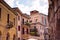Street of Verona with shabby buildings facades and ancient roman theatre in summer cloudy day. Historical italian city Verona,