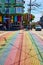 Street view with rainbow crosswalk leading to Gyro Xpress on sunny day