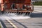 A street washer uses a beam of water jets to wash away dirt from the road. Selective focus