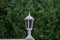 Street white lamp. Green natural background. An old fashioned street lamp. Background blurred, focus only on the lamp.