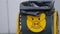 Street yellow-black metal trash can with crossed piggy icon. Urban waste bin