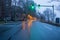 Streetlights reflect off wet street at dawn