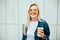 Streetstyle fashion look, pretty cool smiling young woman with coffee cup walking in city, happy female model wearing trendy