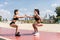 Strength in teamwork. Two young attractive women athletes exercise on the beach doing squats with a sunrise and ocean in the