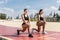 Strength in teamwork. Two young attractive women athletes exercise on the beach doing squats with a sunrise and ocean in the