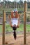 Strengthening her core. A young woman hanging upside down by her legs and using her core to pull herself up.