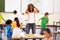 Stress, teacher screaming and black woman in classroom with children running around. Education, headache and female