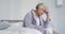 Stressed african american senior woman sitting on the bed at home