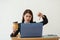 Stressed Asian business woman working on a laptop and showing thumbs down at her office