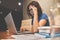 Stressed of Asian eyeglasses Woman with laptop and graph financial diagram documents on wooden table. Headache and migraine.