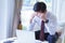 Stressed asian young businessman working with laptop and holding head with hands looking down.