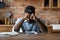 Stressed black man sit by copybooks smartphone overloaded by information