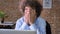 Stressed businessman with curly hair have problems with business, sitting at table with laptop in modern office