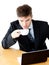 Stressed businessman drinking coffee using laptop
