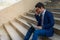 Stressed businessman sit on the stairs and his hands touch his head with sadness caused by a business mistake