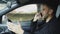 Stressed businessman swearing and talking phone while sitting inside car outdoors