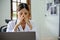 Stressed and exhausted Asian female doctor sitting at her office desk