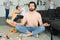 stressed father sitting in lotus pose on floor and sons playing around